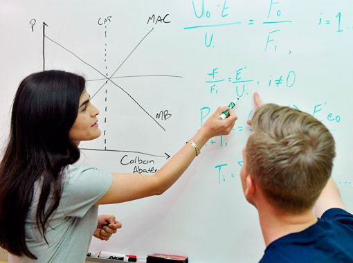 
                two students working on a white board
            