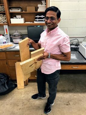 Kaushlendra Singh stands in his lab holding the three types of wood he is using for this research project: birch, red oak and longleaf pine.