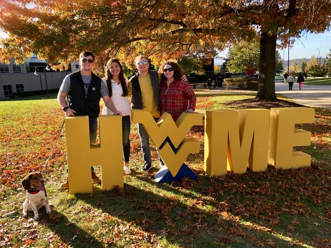 Photo of family of four standing with WV 'home' sign.