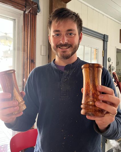 Photo of young man holding wooden air plant holders. 