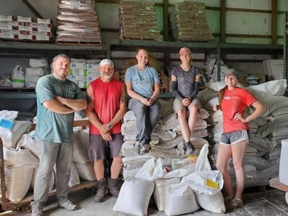 Group of people smile for picture standing in a feed mill.