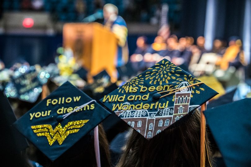 Decorated graduation caps. One says Follow your dreams; while the other one says Its been wild and wonderful.