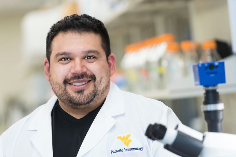 Javier Garza wearing Parasite Immunology lab coat