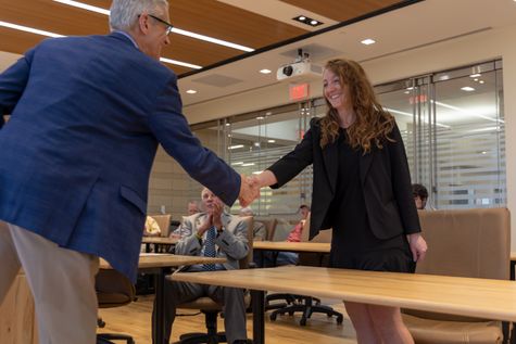 Photo of young woman shaking hands with older man.