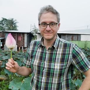 Andrew in a garden holding a lotus flower.