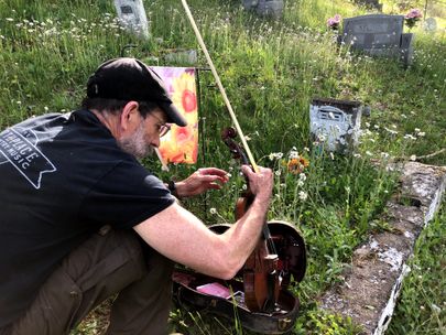 Chris Haddox with his violin at a grave site. 