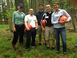 Students in forest holding orange helmets