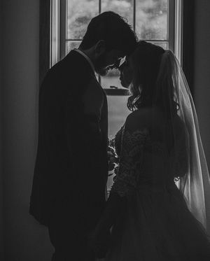 Bride and groom in front of window