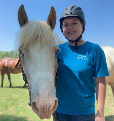 Victoria Chisler wearing a CHEFF shirt stands with a horse