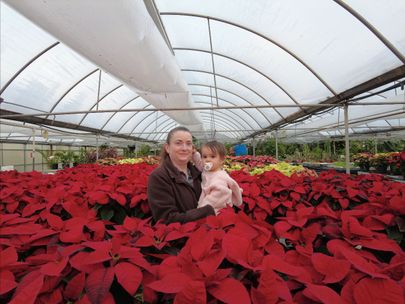 Nicole Waterland with her daughter in a greenhouse of poinsettias.