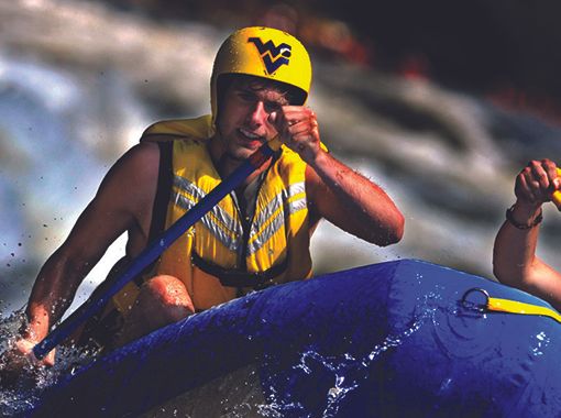 man in raft paddling in whitewater